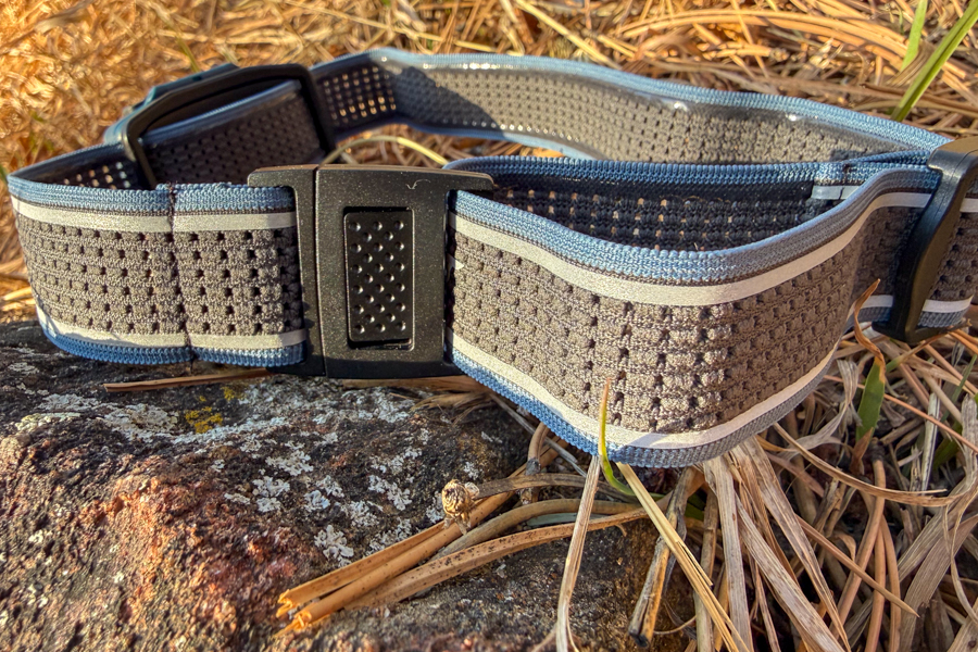 Detail shot of the Coast headband strap and adjustment buckle laid out on a rock in dry grass.