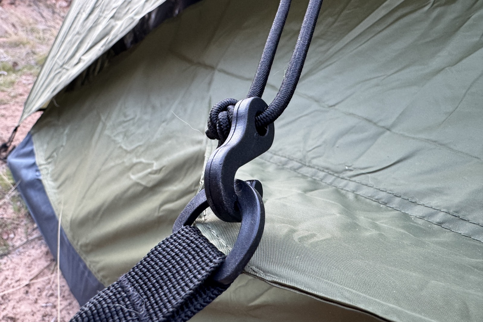 Close up of a plastic hook attached to a plastic D ring on the side of the Trekker tent. Both are attached to other parts of the tent.