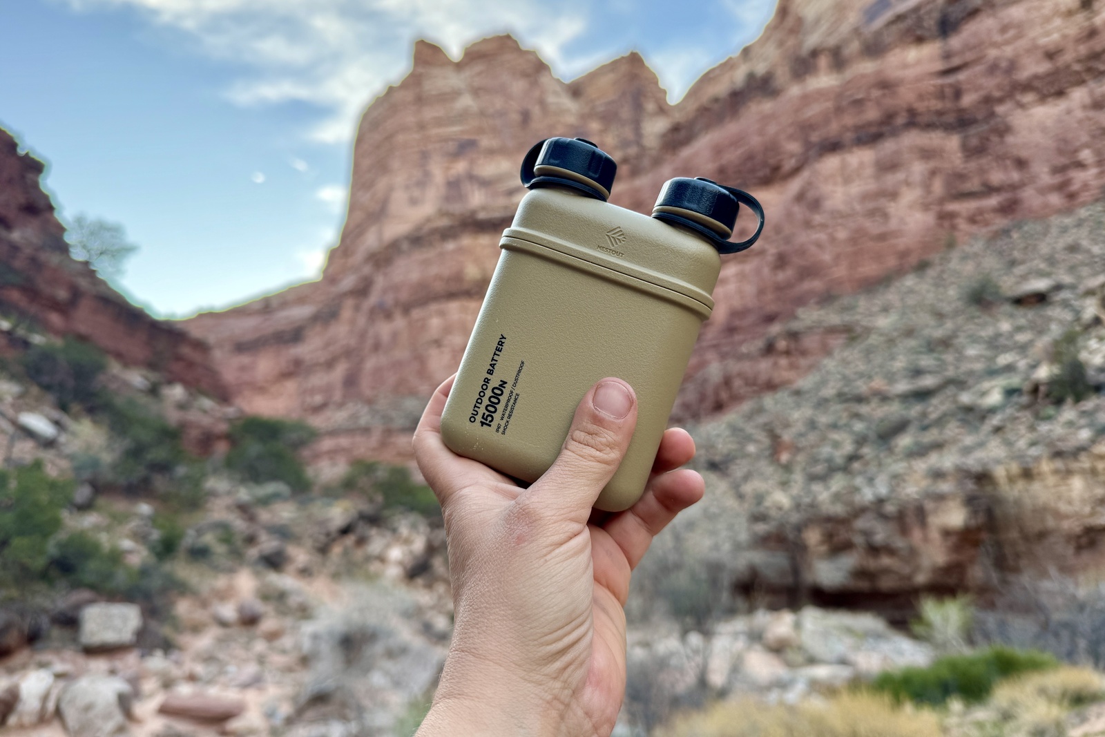 Close up of a hand holding the Nestout up. There is a red cliff and canyon in the background.