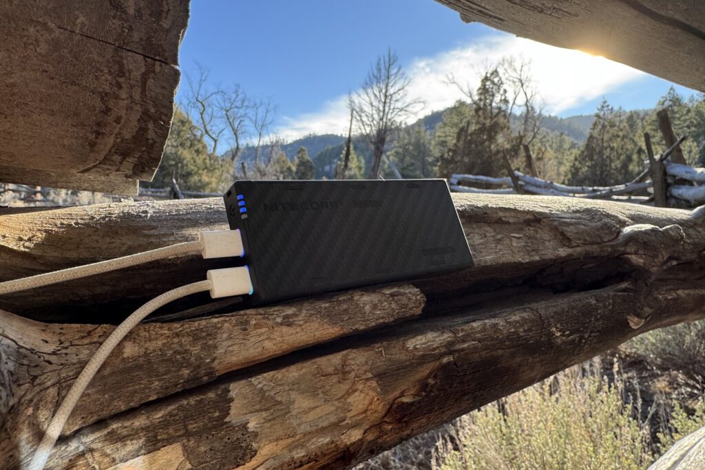 Hay dos cables conectados al NB10000 Gen 4. Primer plano sobre una valla dividida con algunos árboles y montañas al fondo.