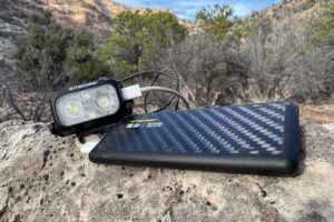 Closeup of the NB Air sitting on a rock charging a Nitecore headlamp. There is a pinion-juniper forest in the background.