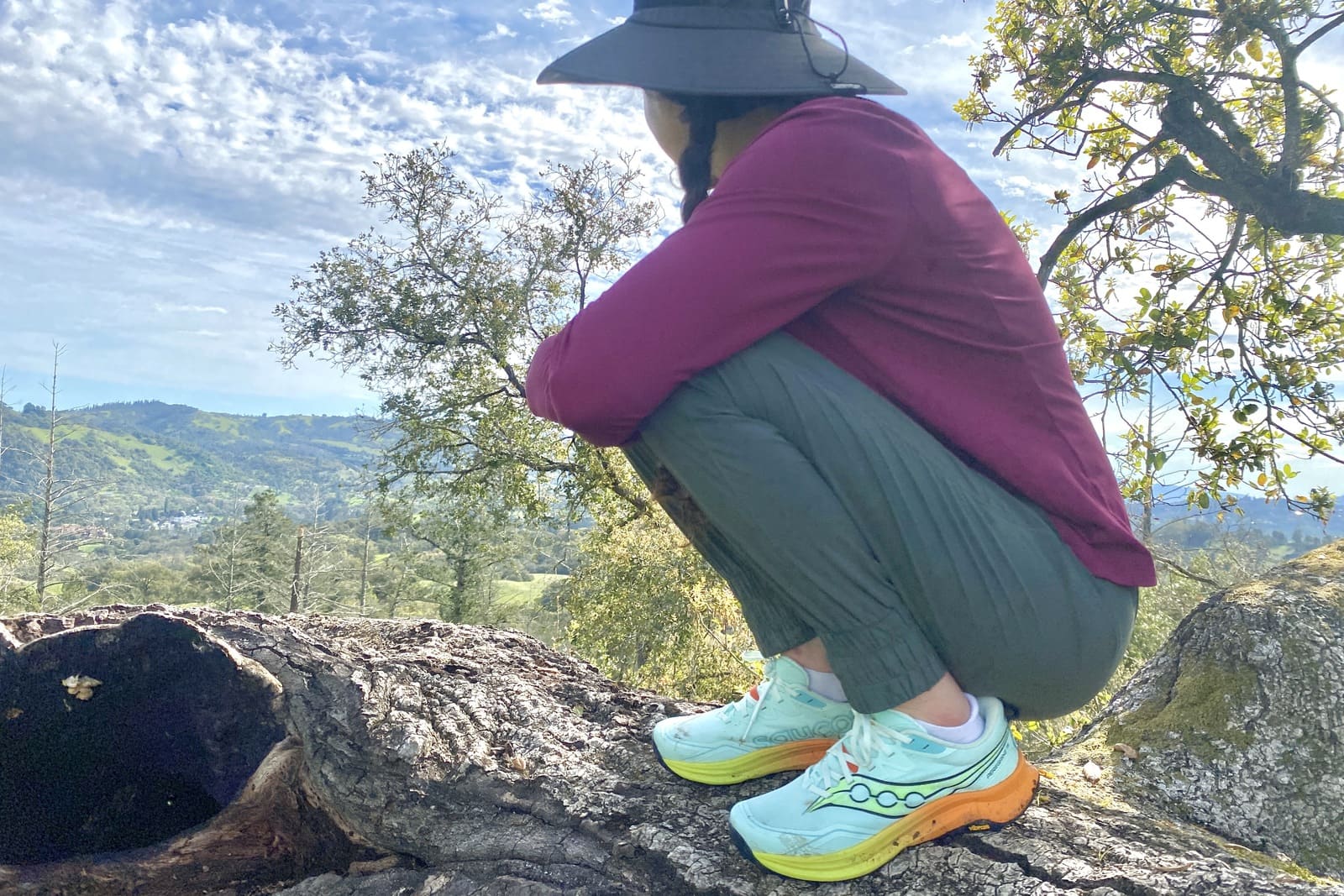 A woman crouches at an overlook.