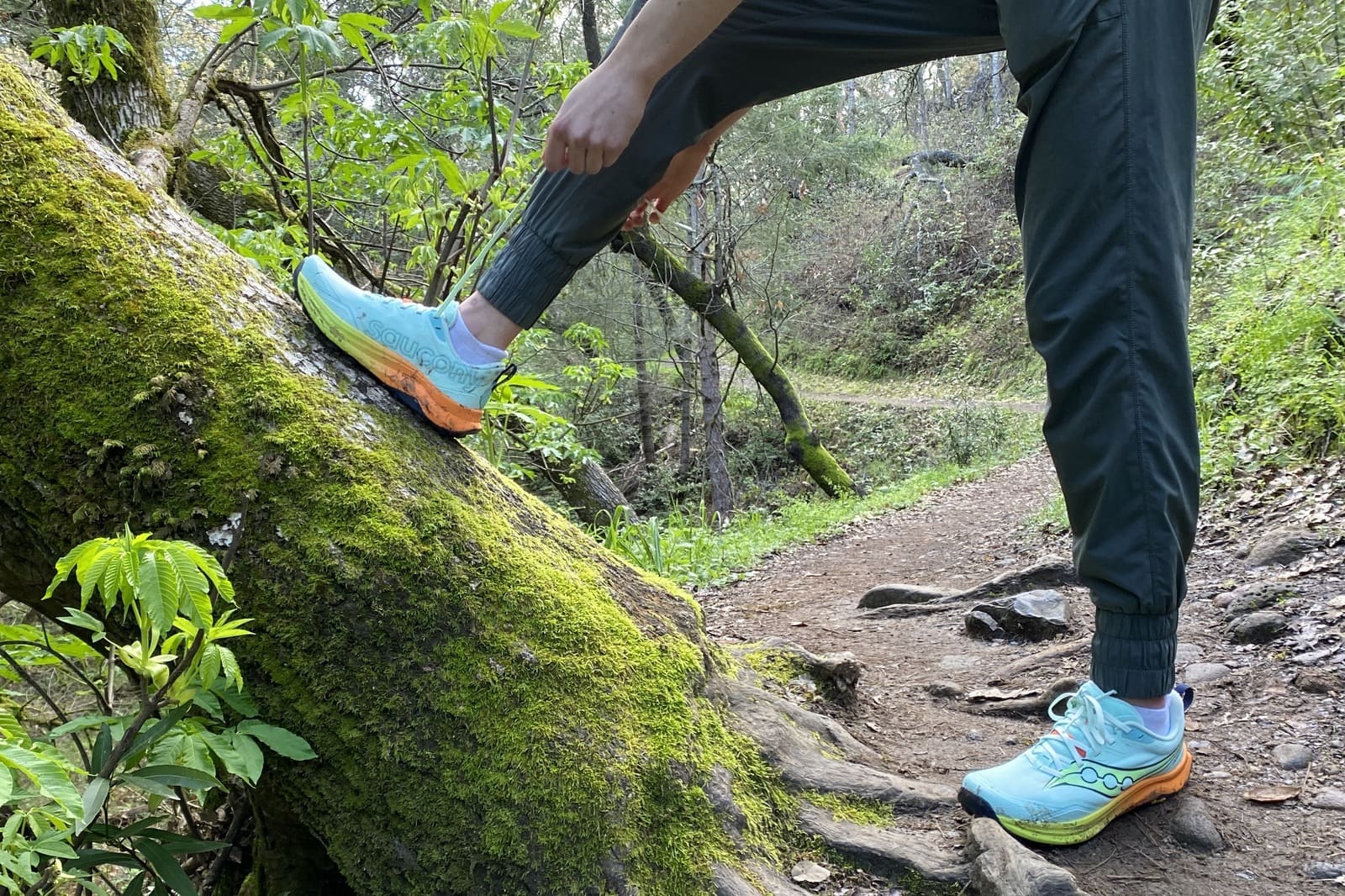 A woman laces up her shoes on the trail.