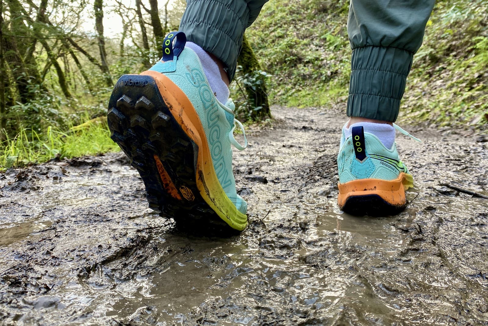 Closeup showing tread on the bottom of shoes after hiking through mud.