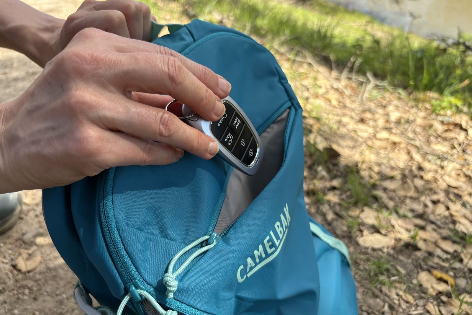 A woman puts a key in the smaller outer pouch of her pack