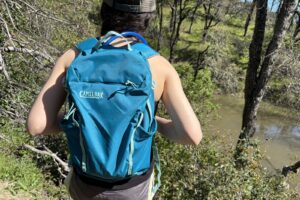 A woman hikes, a long trail wearing her hydration pack.