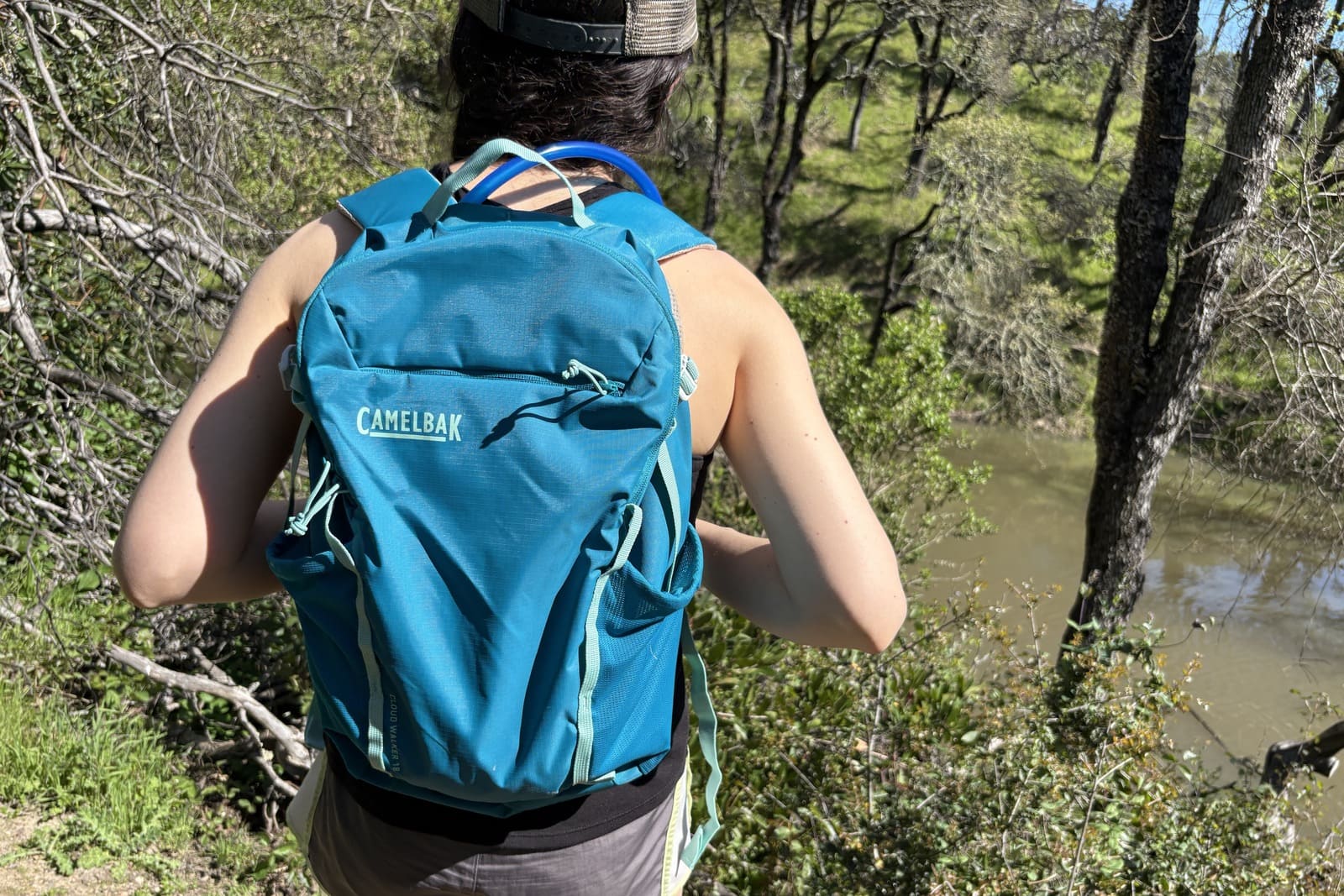 A woman hikes, a long trail wearing her hydration pack.