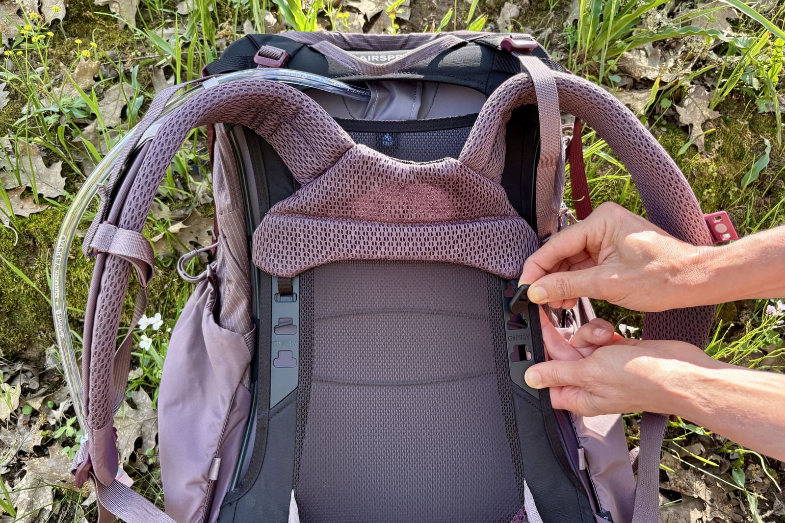 A woman shows the adjustable torso on her backpack.