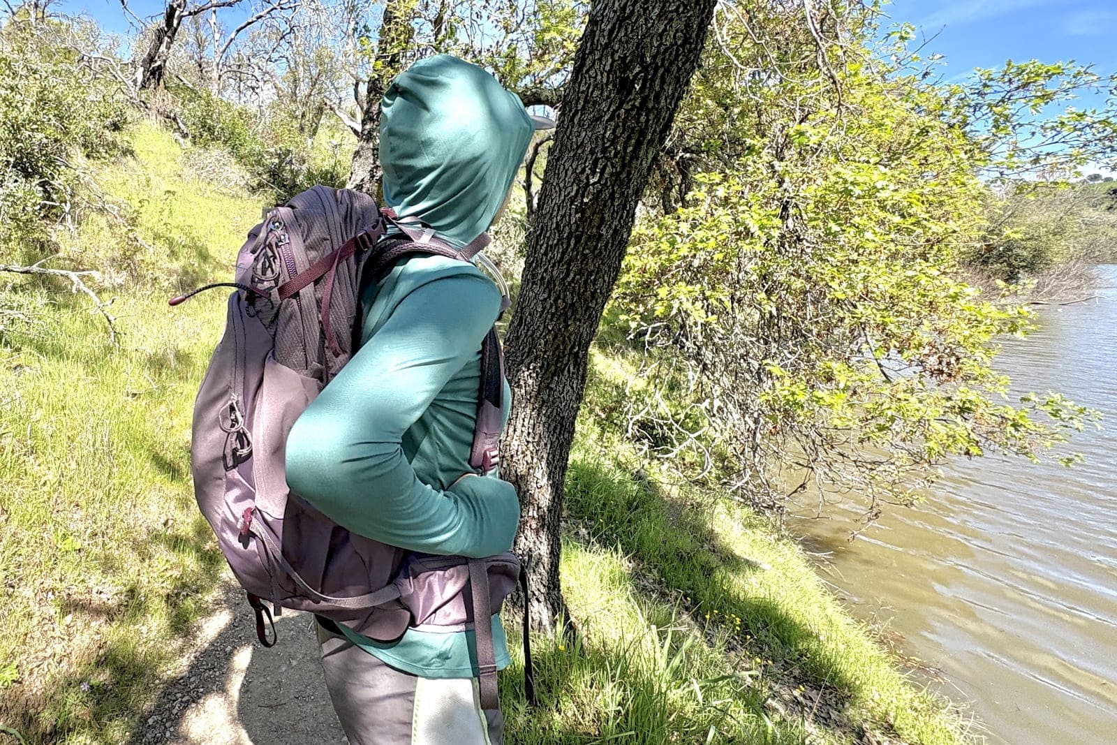 A woman stands on a trail with her daypack