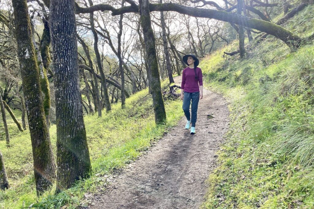 A woman walks along a forested trail.