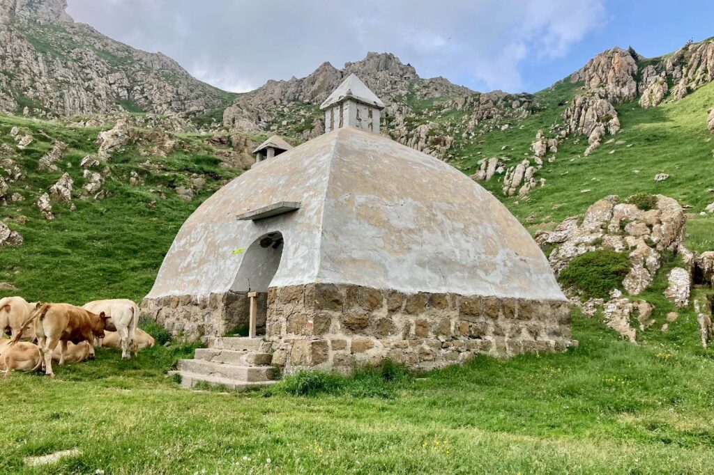a domed concrete structure in the mountains with cows around it