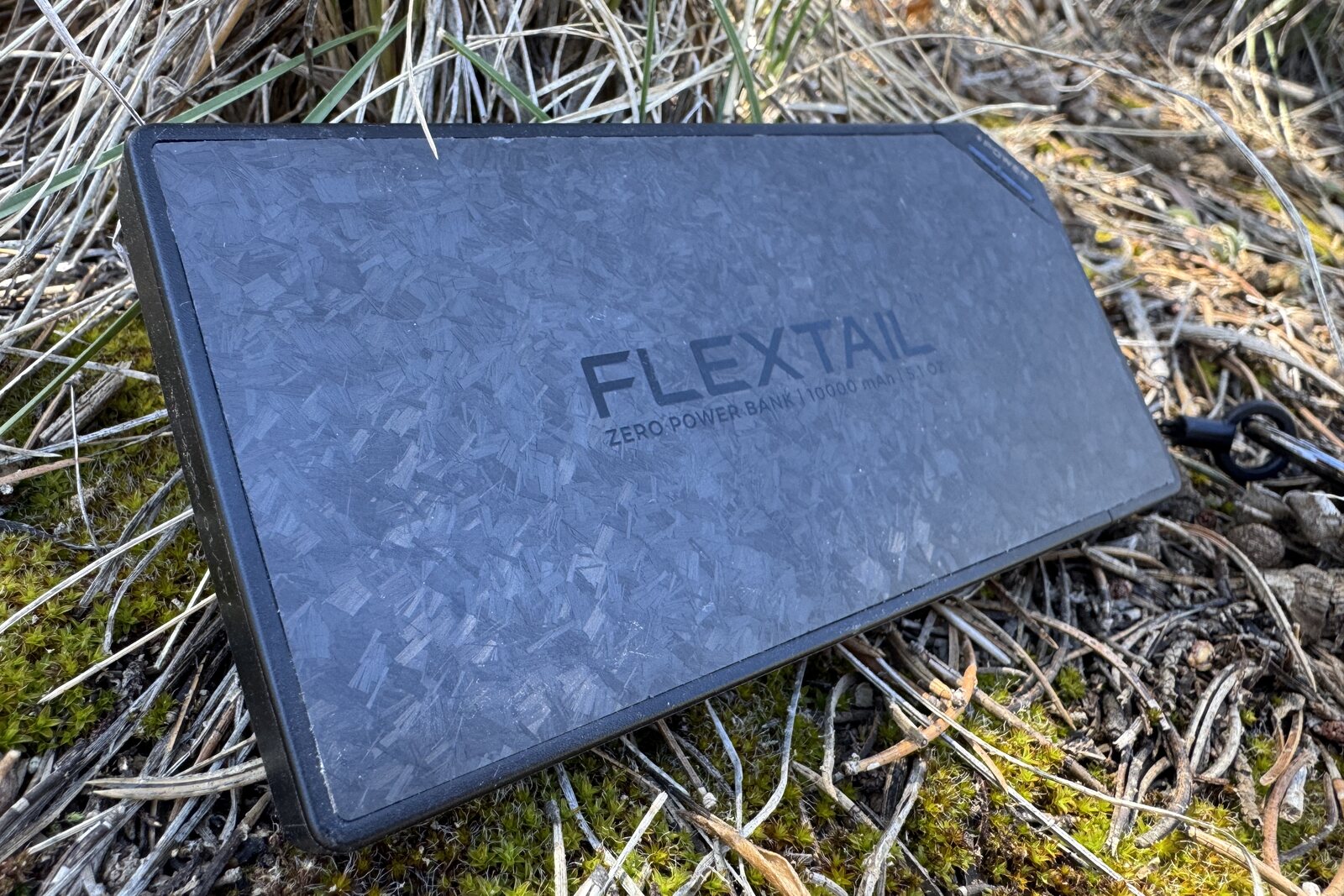 Close up of the Flextail power bank sitting on some grass and moss.