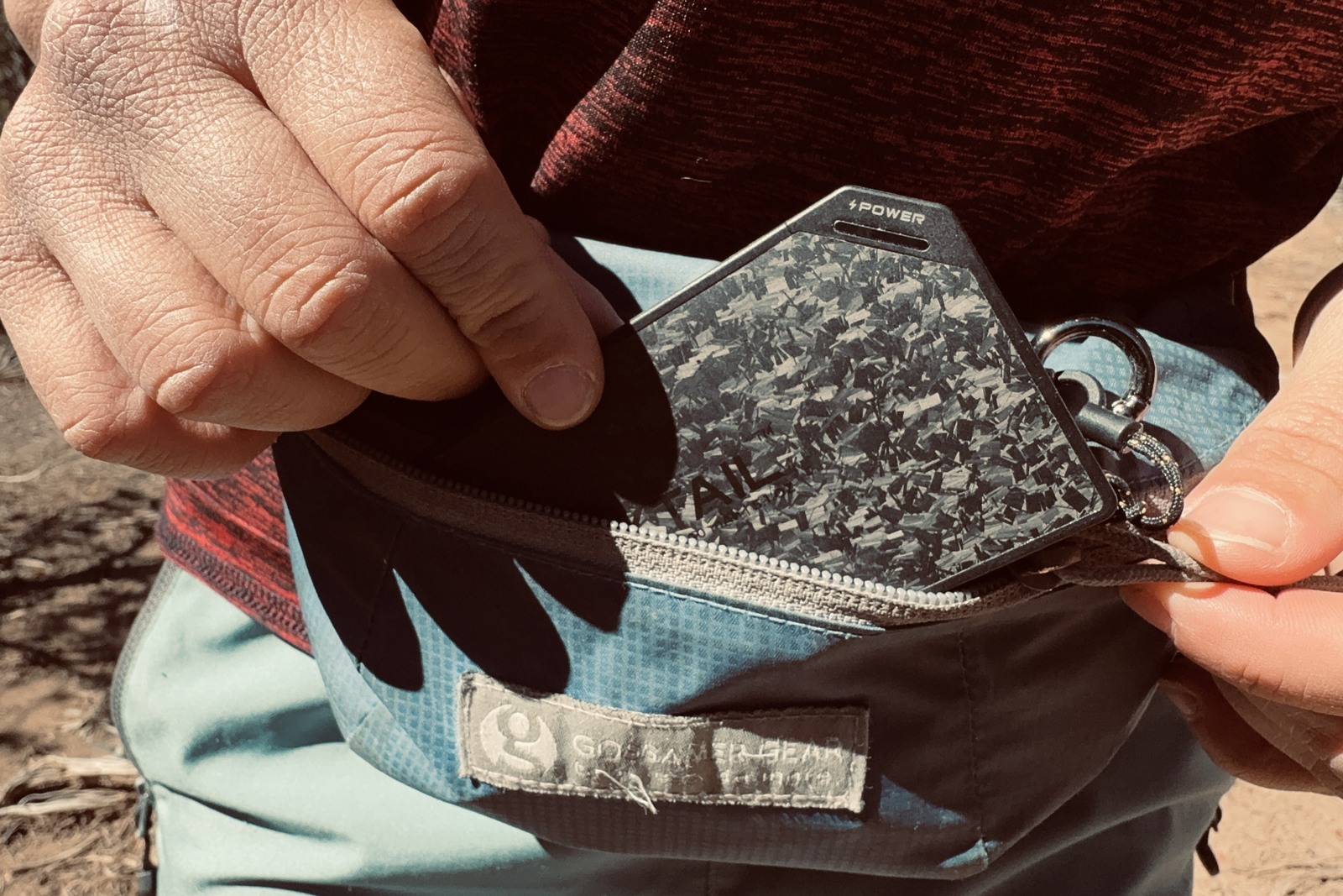 Close up of a hand taking the Flextail power bank out of a fanny pack.