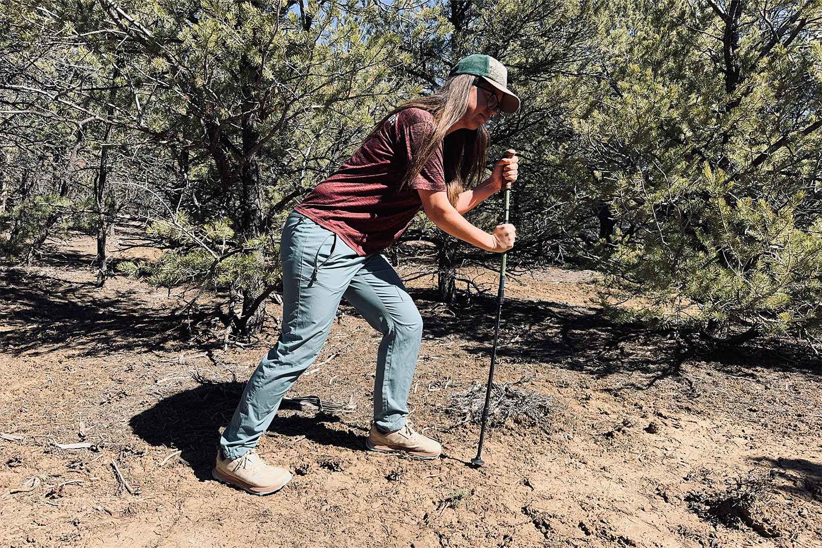 A person is leaning on the Legacy poles with pinion and juniper trees in the background.