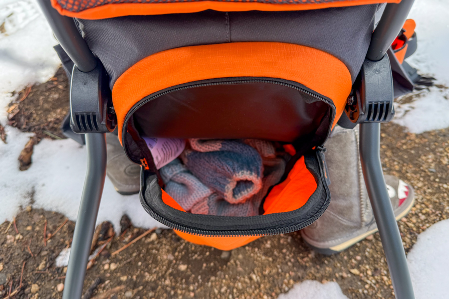 Top-down view of the Luvdbaby Premium lower storage pocket unzipped and partially filled with extra clothing.