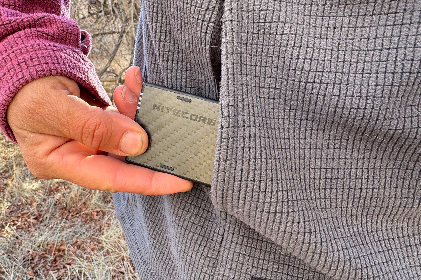 Un primer plano de alguien sacando el NB10000 del bolsillo de una chaqueta polar.