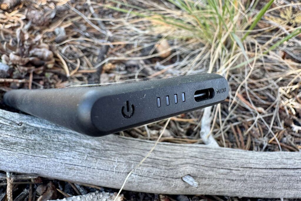 A close up showing the single charging port, charge indicator, and power symbol on the NB Air. It is balanced on some sticks on the ground.