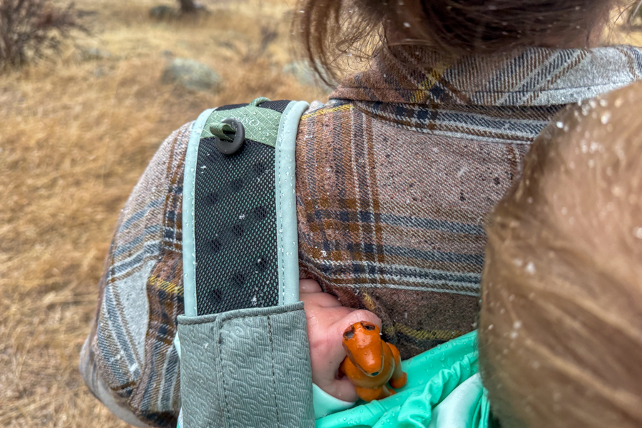 Close-up of the Osprey Poco Soft shoulder strap and upper child seat area, with a toy dinosaur visible next to the child’s hand.
