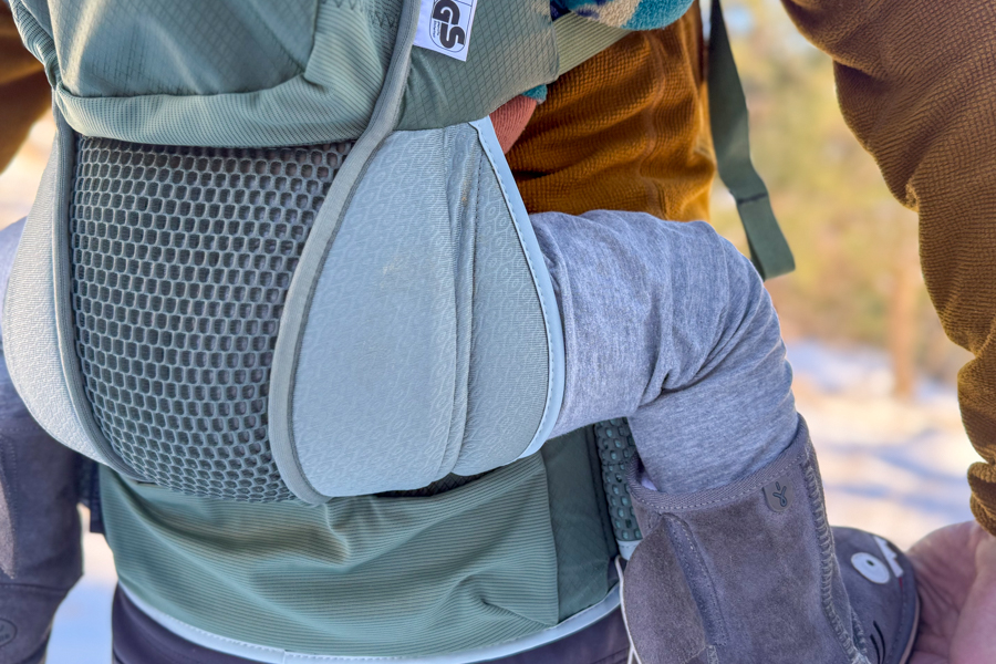 Close-up of the Osprey Poco Soft seat and lower back panel, showing the child’s leg position and the carrier’s padded support panels.