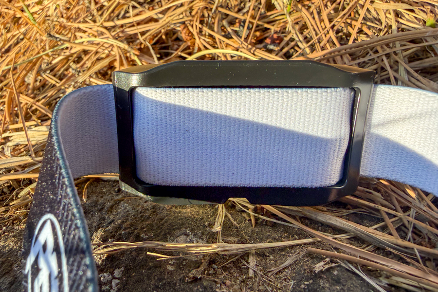 Detail shot of the Petzl headband strap and plastic adjustment buckle lying on a rock.