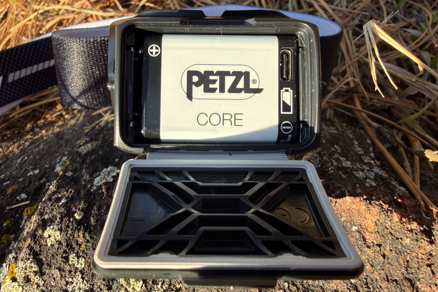 Petzl headlamp battery compartment open, showing a Petzl CORE rechargeable battery and the USB charging port.