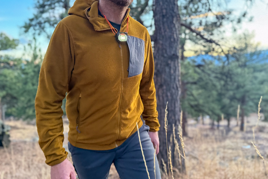 Person wearing the Petzl Swift headlamp around their neck, using it as a chest light while standing outdoors at dusk.