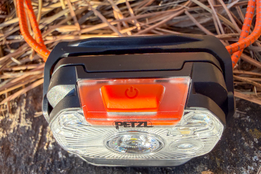 Top view of the Petzl Swift headlamp showing the large orange power button and Petzl logo above the clear lens.