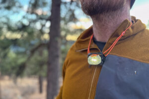 Close-up of the Petzl Swift headlamp worn around the neck like a necklace, shining light onto a jacket.