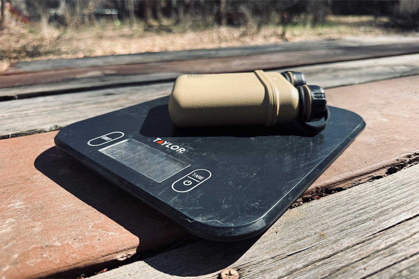 Close up of the Nestout sitting on a kitchen scale. They are both sitting out in the sun on a picnic table.