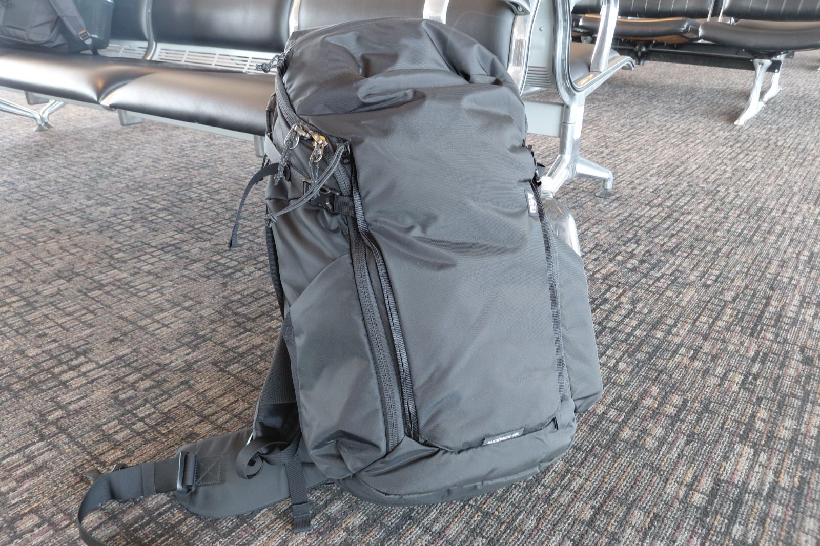 A backpack rests against seats in an airport.