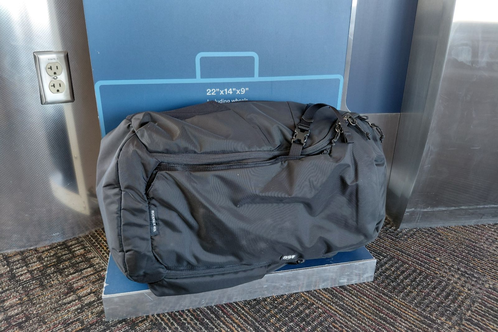 A blackpack sits in a luggage sizer.
