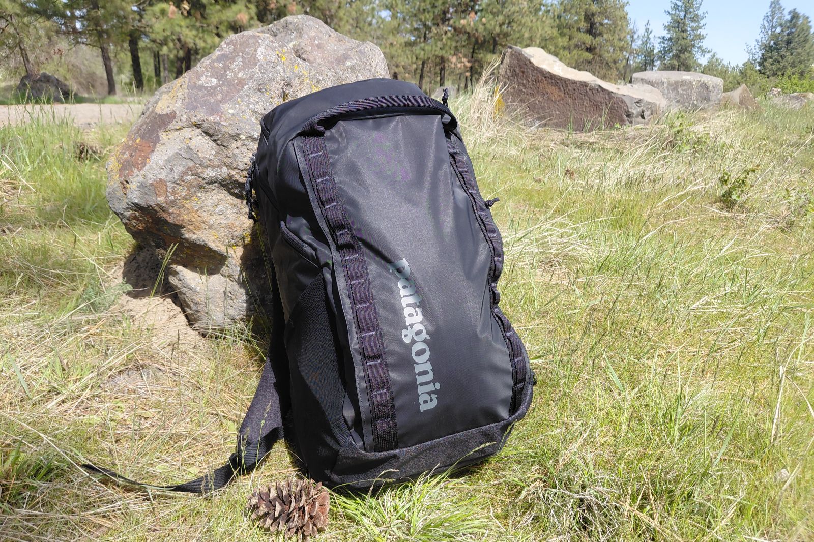 A backpack leans against a rock, showing the external material.