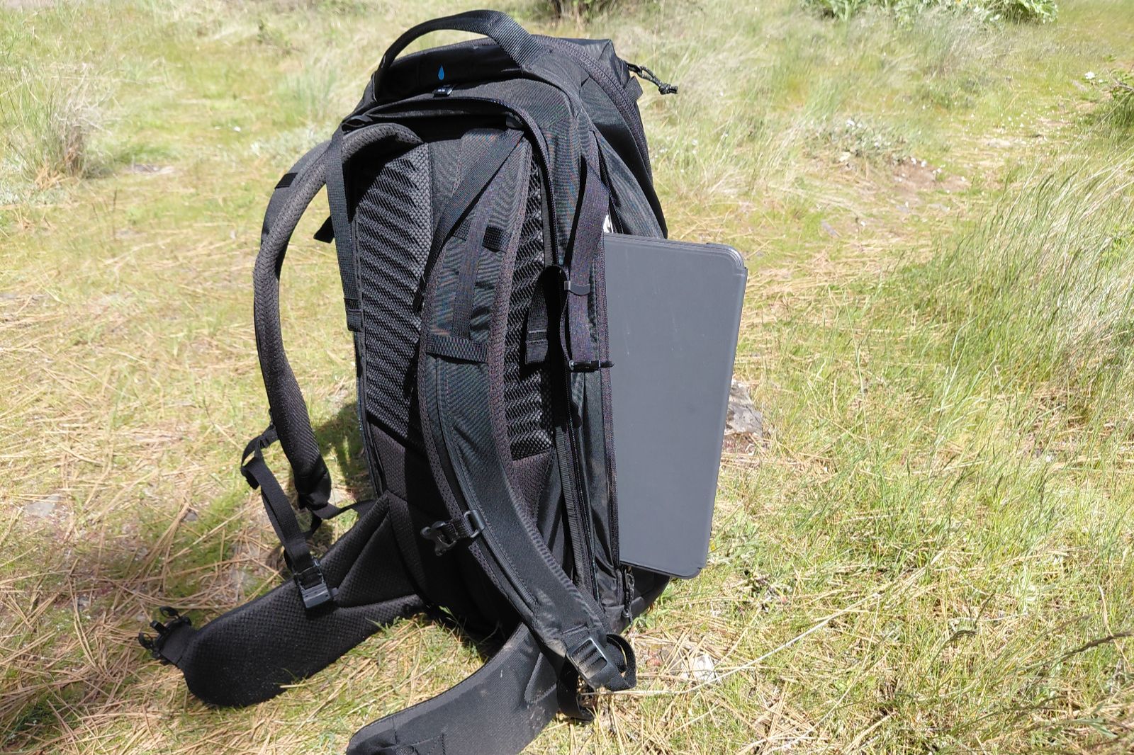 A black backpack shows the laptop compartment with a device halfway out of it.