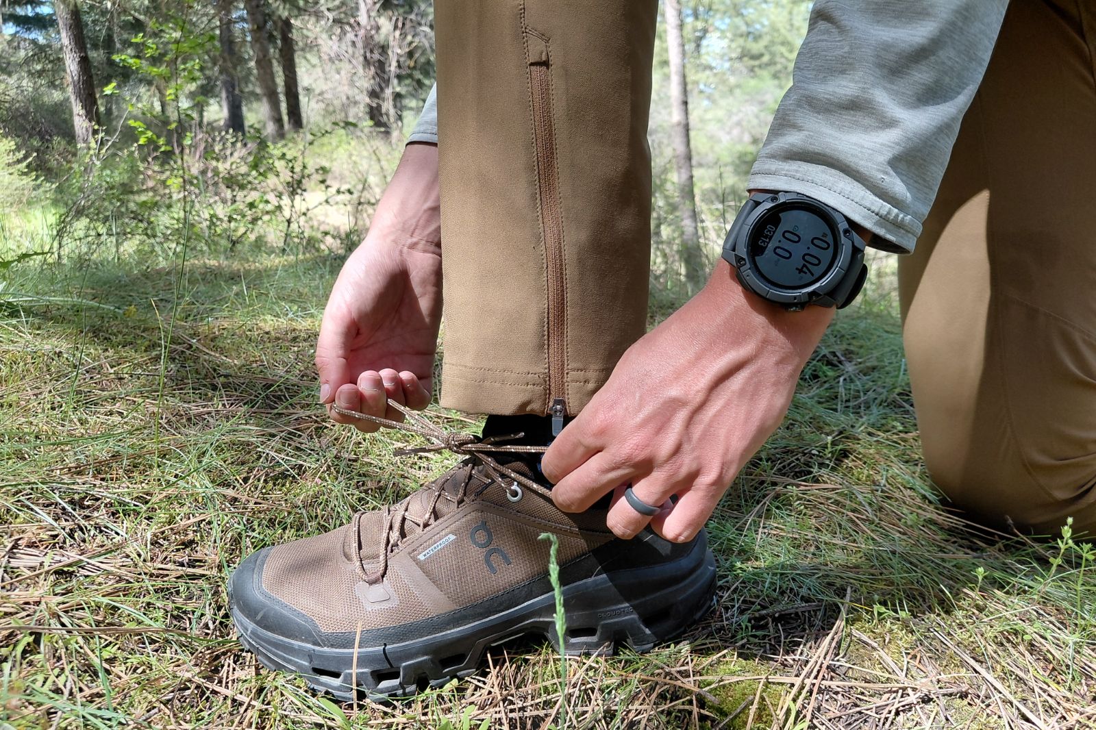A close-up of the wrist of a watch as a man ties his shoes.