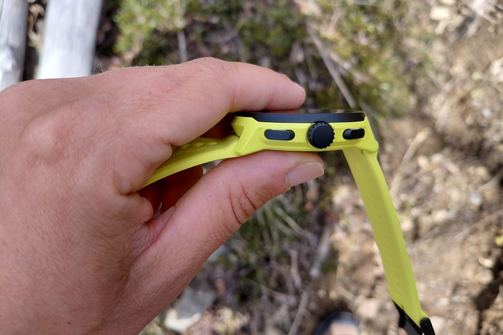 A person holding a yellow GPS watch showing the buttons on the side.