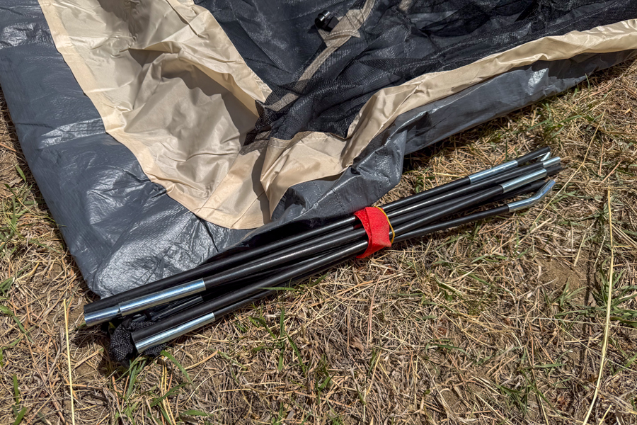 Close-up of the Coleman Skydome 4 tent's pre-attached poles bundled next to the tent body during setup.