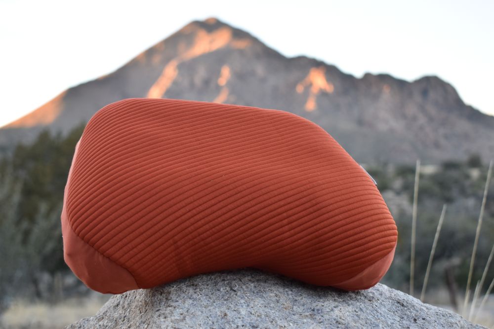 The curved shape of the Aeros Premium pillow in the foreground with a mountain blurred in the background.