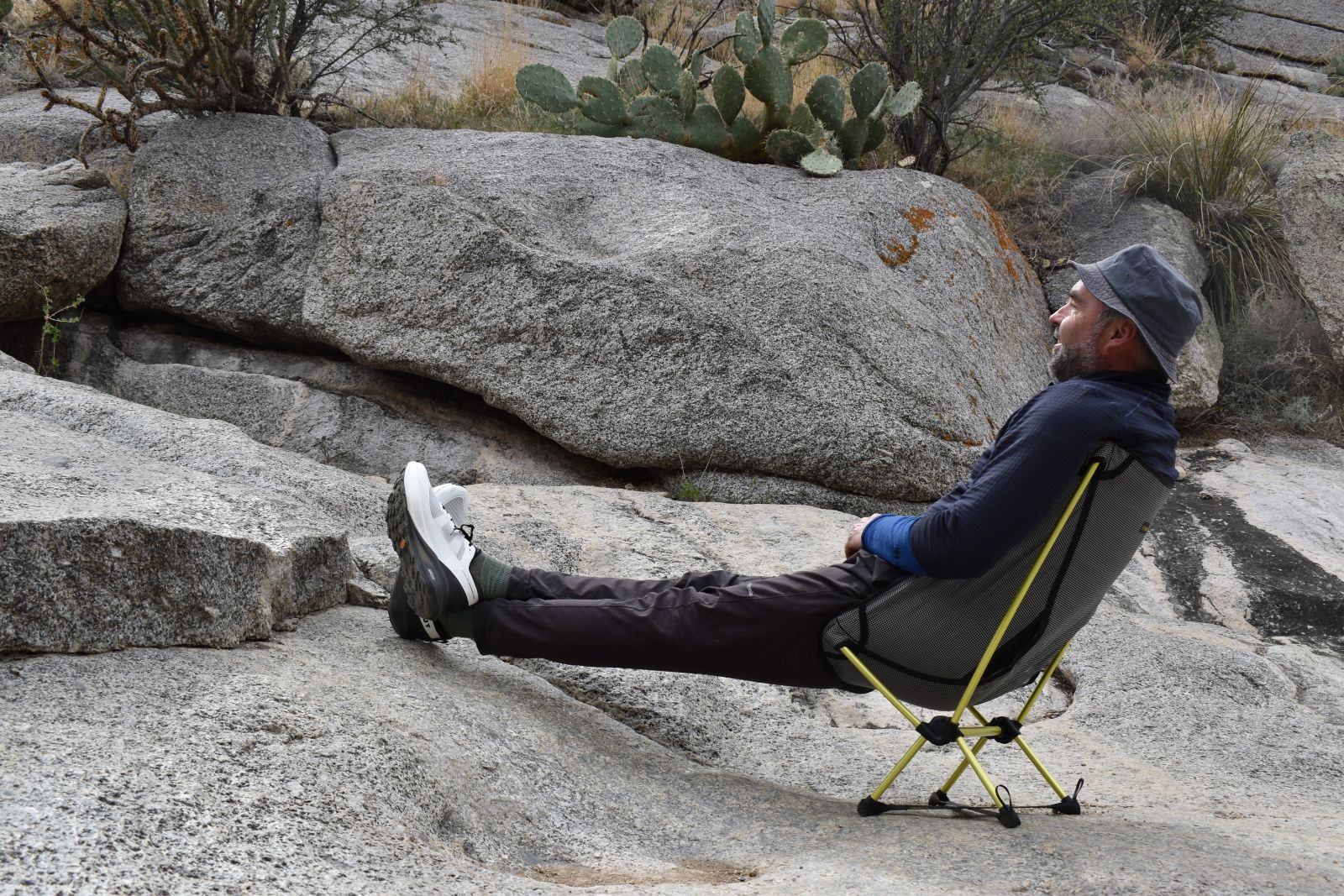 Un mochilero se recuesta en una silla de mochilero con los pies elevados sobre una roca.