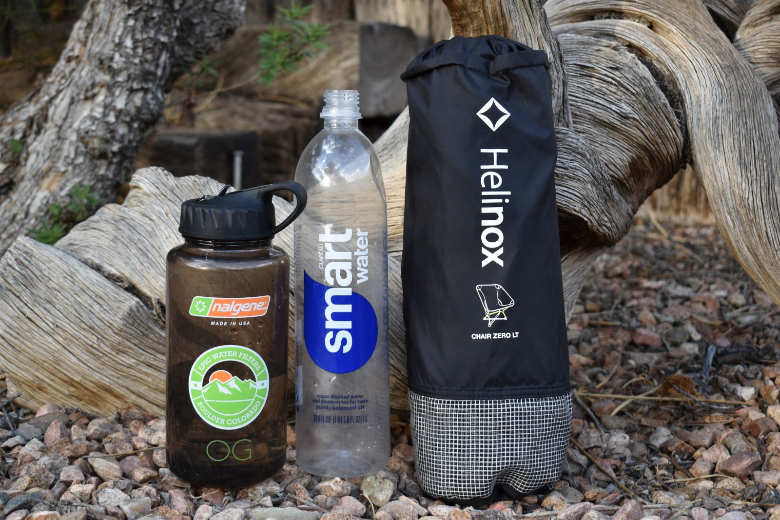 Una botella de Smartwater de Nalgene y una silla Helinox LT en su bolsa de cosas alineadas de izquierda a derecha.
