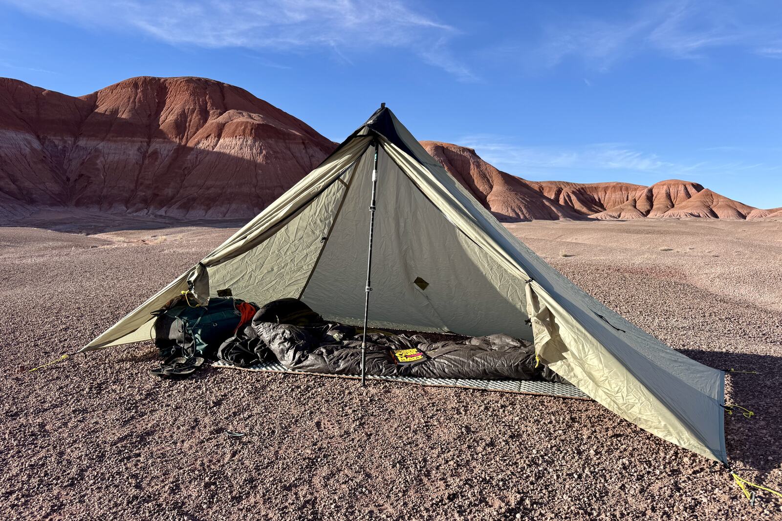 The MLD tent is setup in the badlands with a backpack, sleeping pad, and sleeping bag inside. Both doors are open providing a lot of sunshine and space.