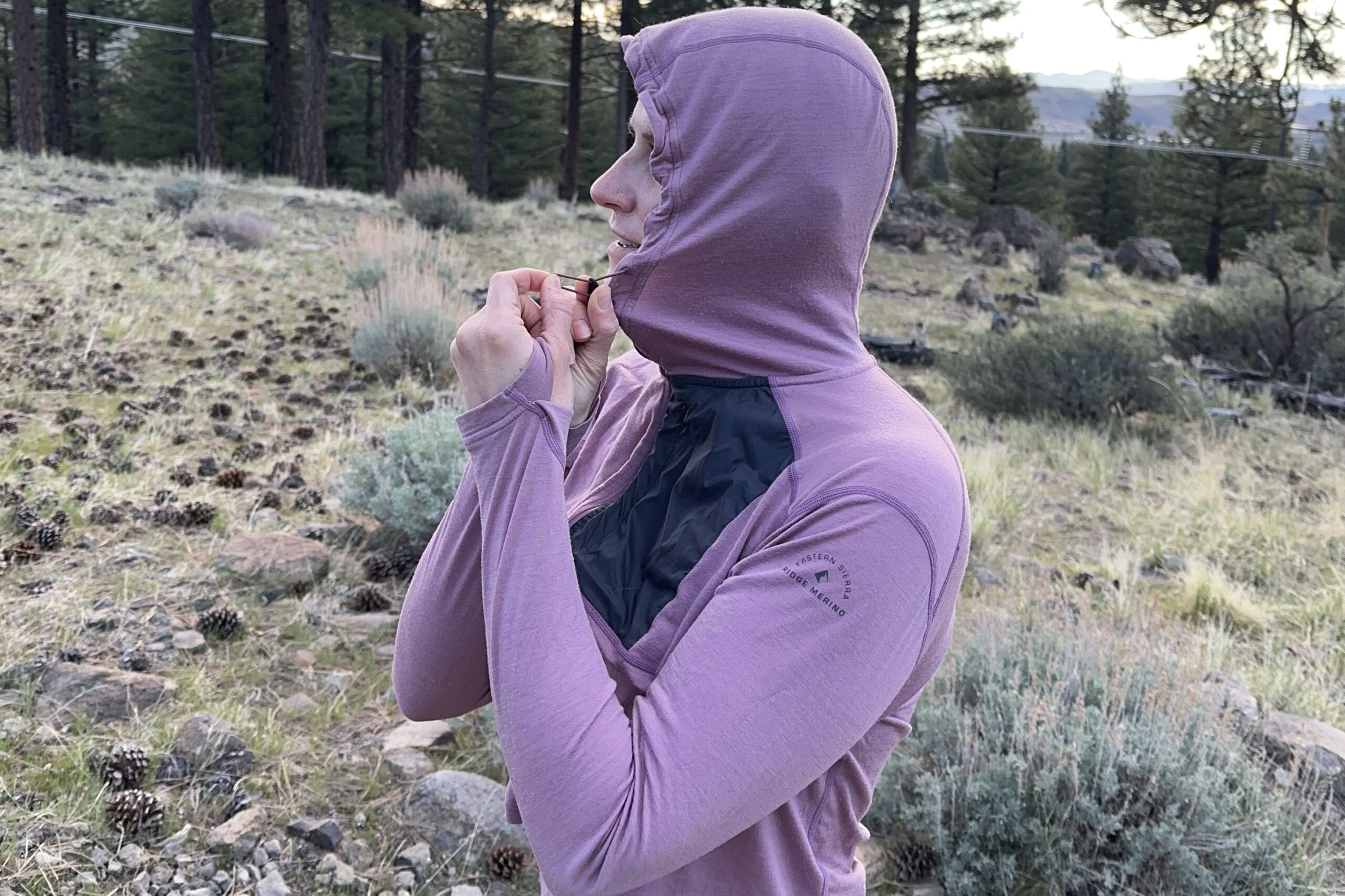 A woman pulls on the hood of her shirt's drawstrings to tighten the hood.