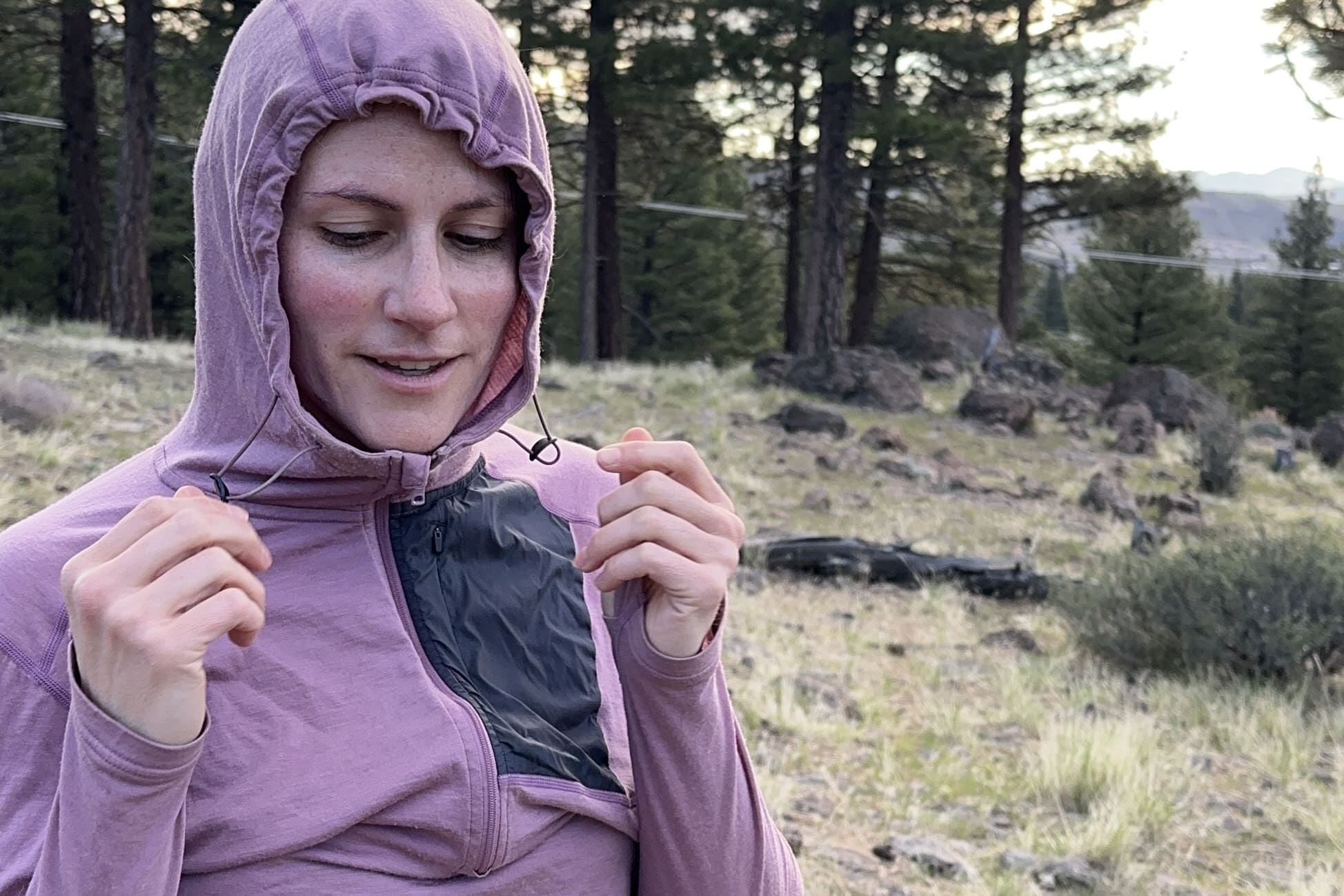 A woman pulls on the hood of her shirt's drawstrings to tighten the hood.