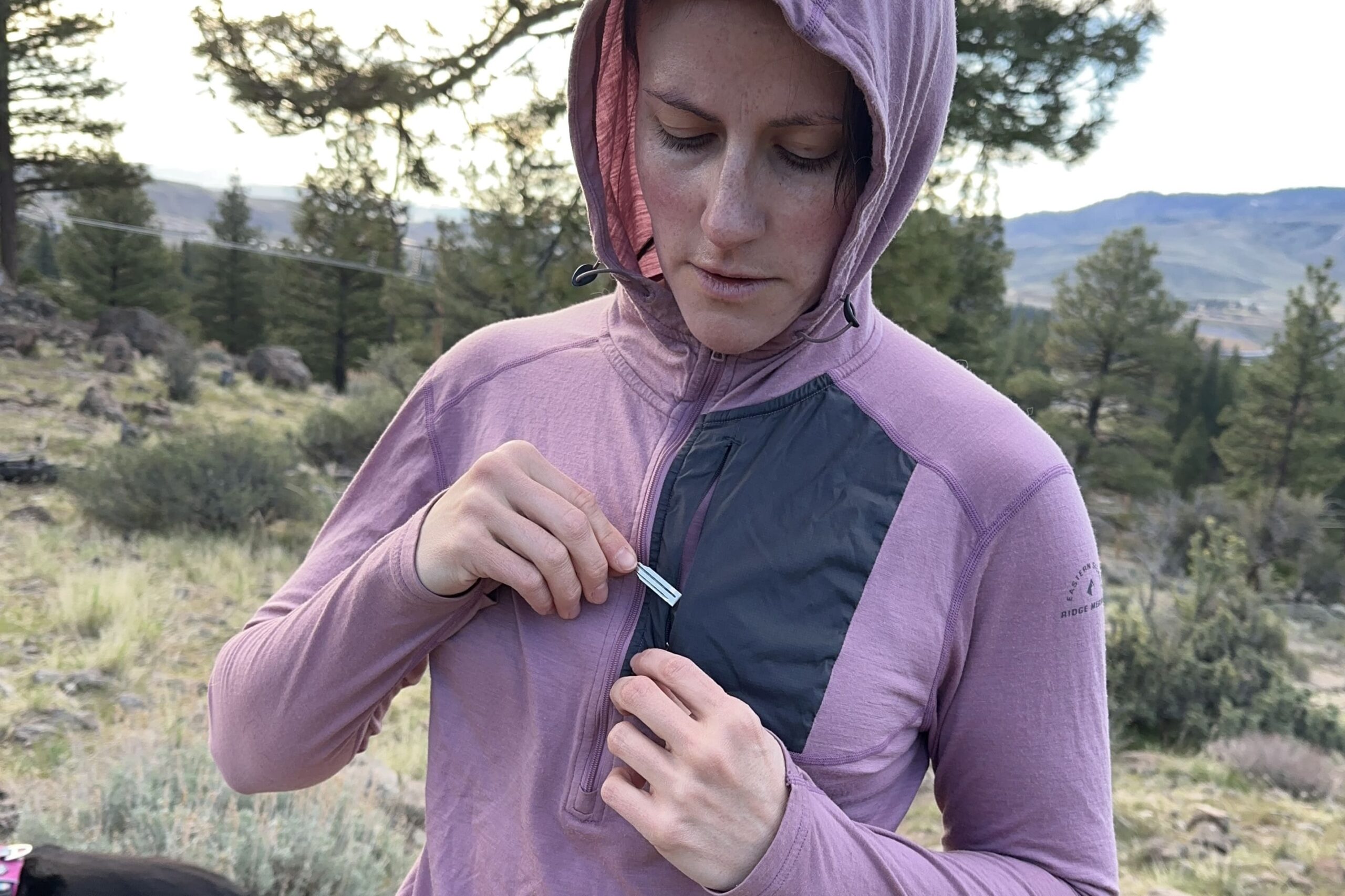 A woman puts a key into the pocket at the chest of her sun shirt.