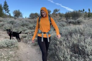 A woman hikes in a bright orange shirt.