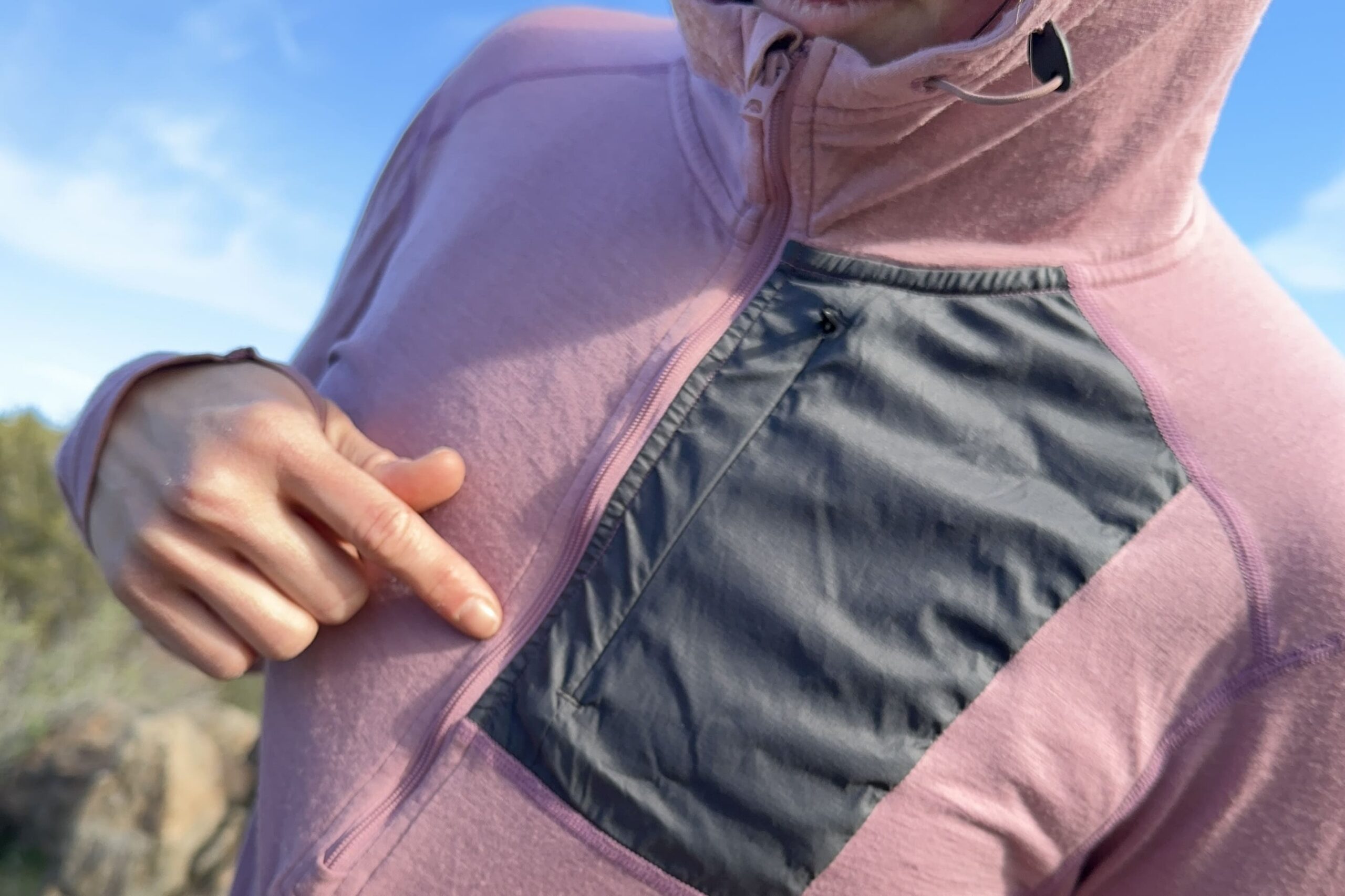 A woman points to the zipper on her sun shirt to show how it buckles.