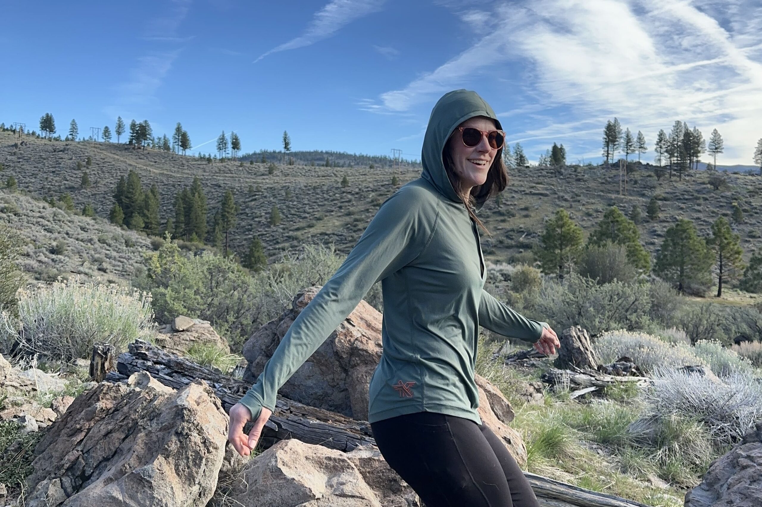 A woman smiles and looks into the distance while hiking trail in the high desert.