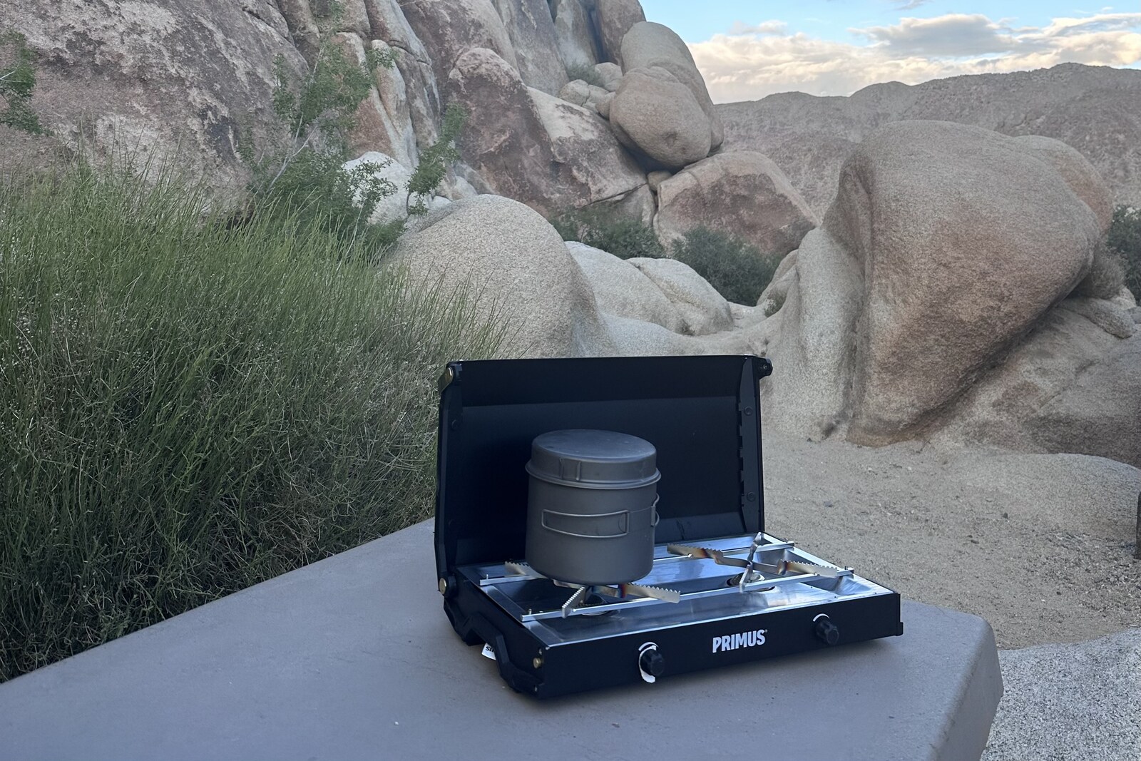 A small pot sits on top of a small, black double-burner stove on a picnic table in Joshua Tree National Park.