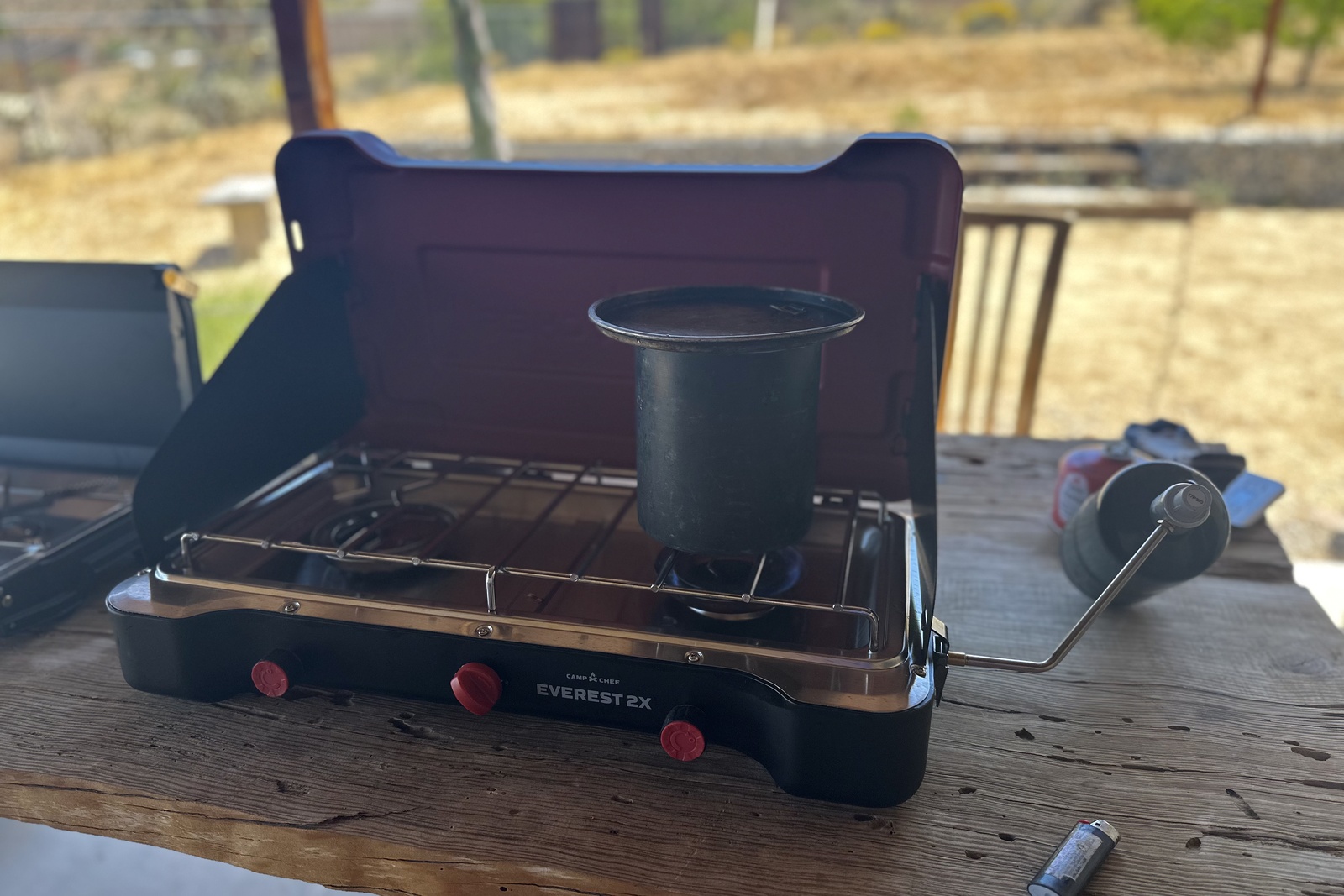 Close-up image of a pot of water on one of the burners of a large double-burner stove with a red hood.