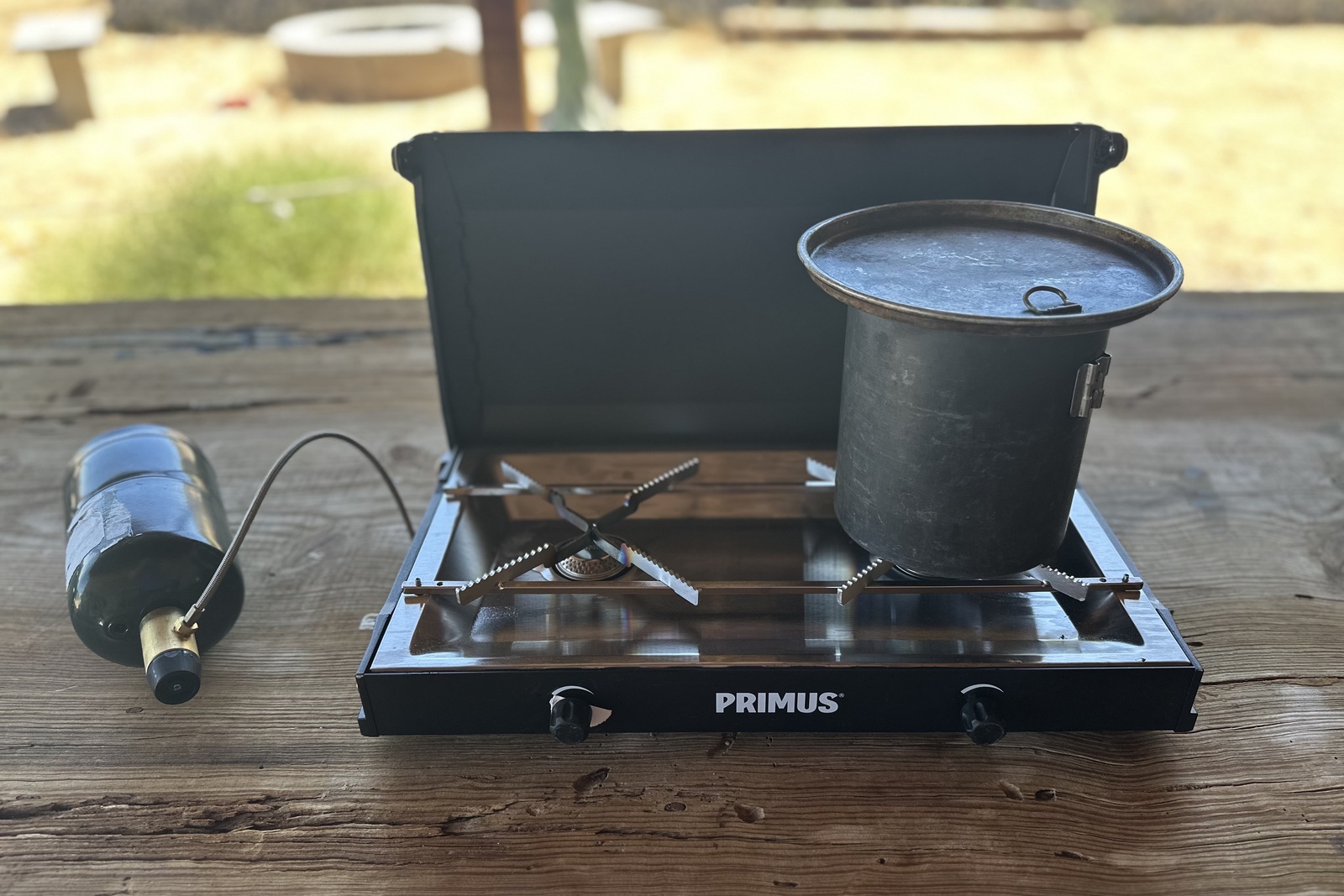 Close-up image of a pot of water on top of a small, black double-burner stove.