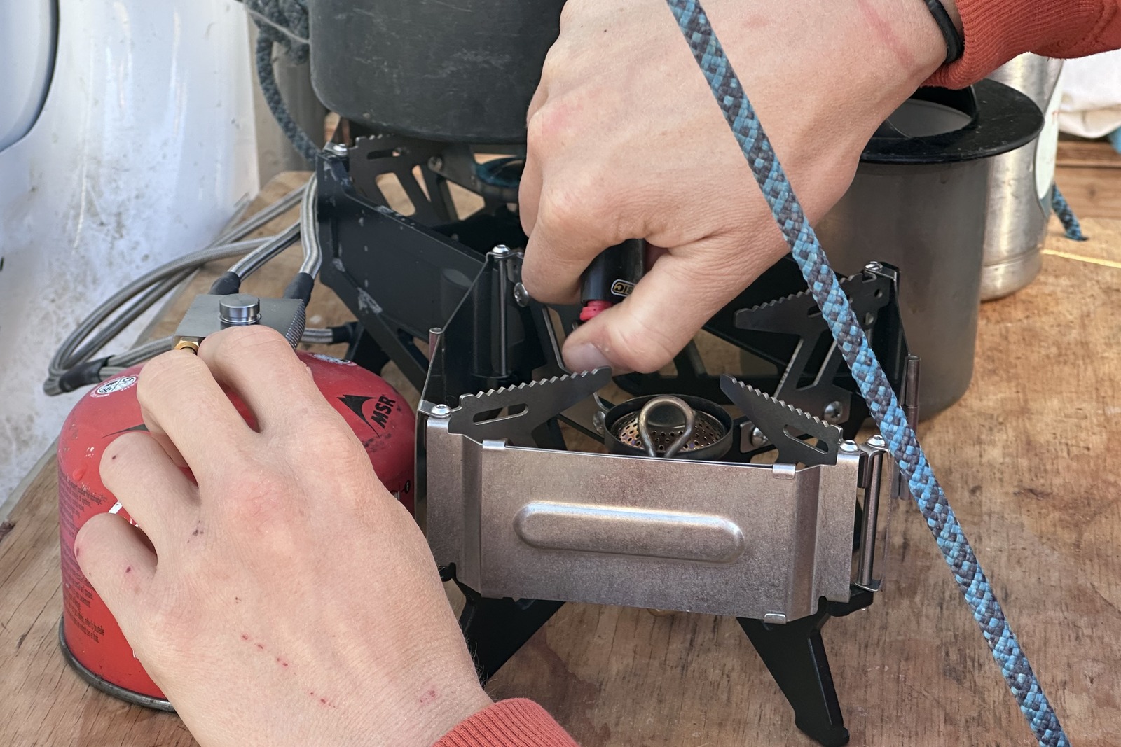 Close-up image of a hand lighting one of the burners on a small double-burner stove with a lighter.